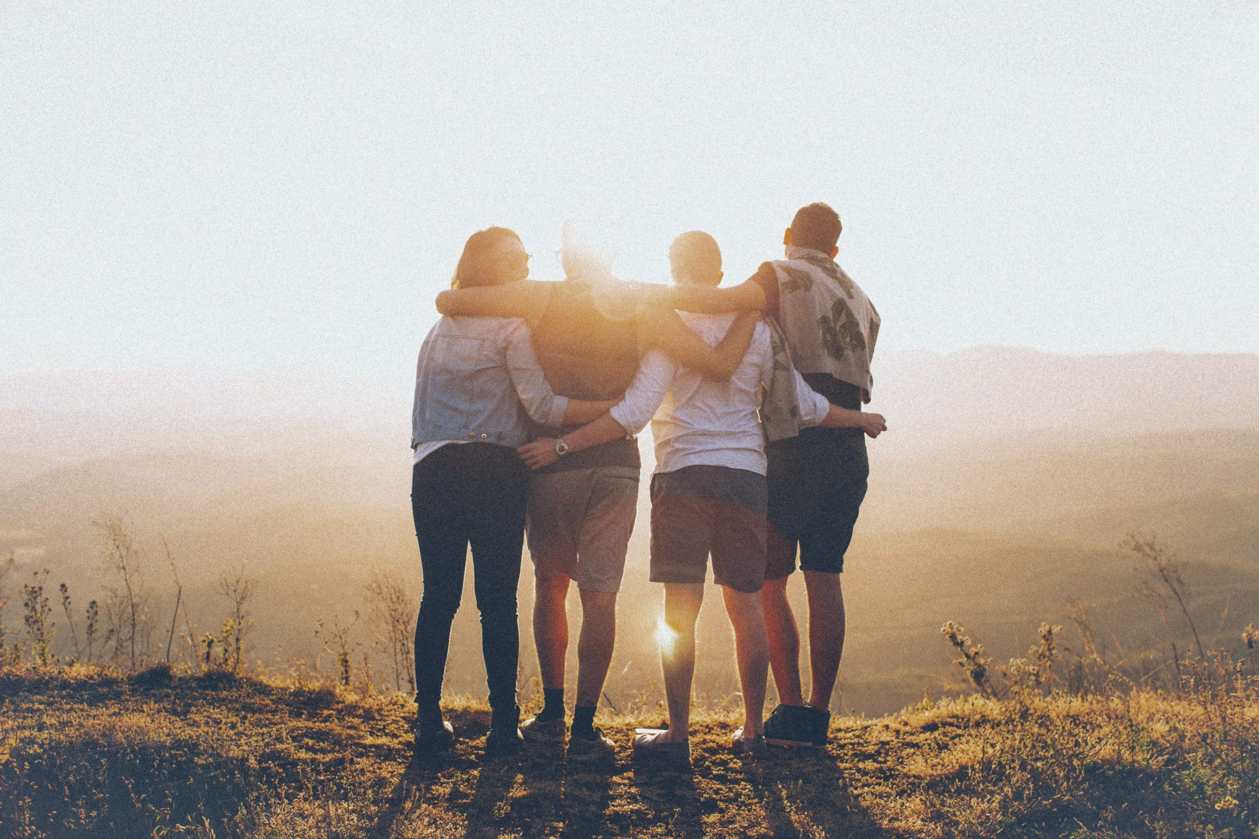 Friends with their arms around each other at sunset.