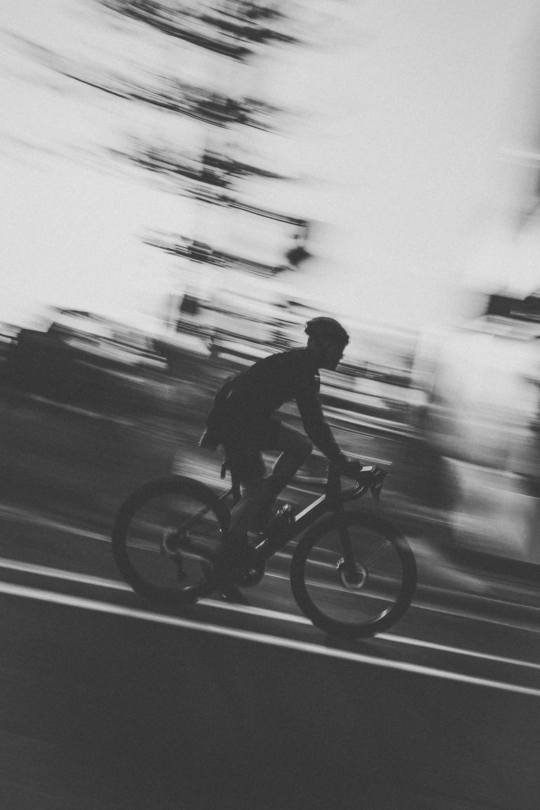A cyclist on an open road, in black and white.