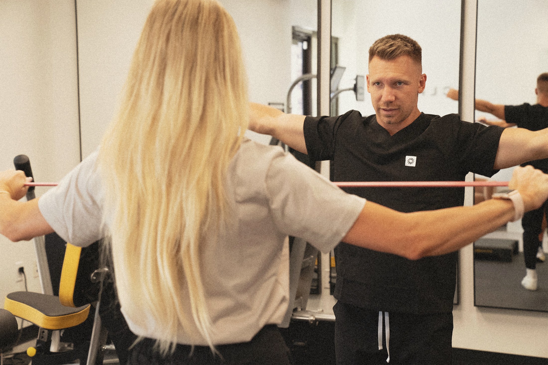 A Clay coach working through a resistance band movement with a member during a check-in.